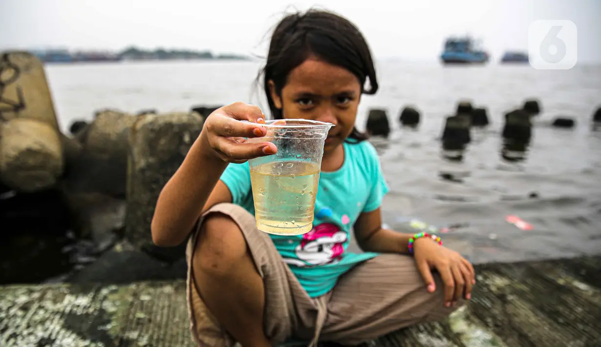 Seorang anak menunjukkan air dari Kali Adem, Muara Angke, Jakarta Utara, Sabtu (2/10/2021). Teluk Angke dan Ancol yang ada di wilayah Jakarta Utara dilaporkan tercemar paracetamol dengan konsentrasi tinggi. (Liputan6.com/Faizal Fanani)