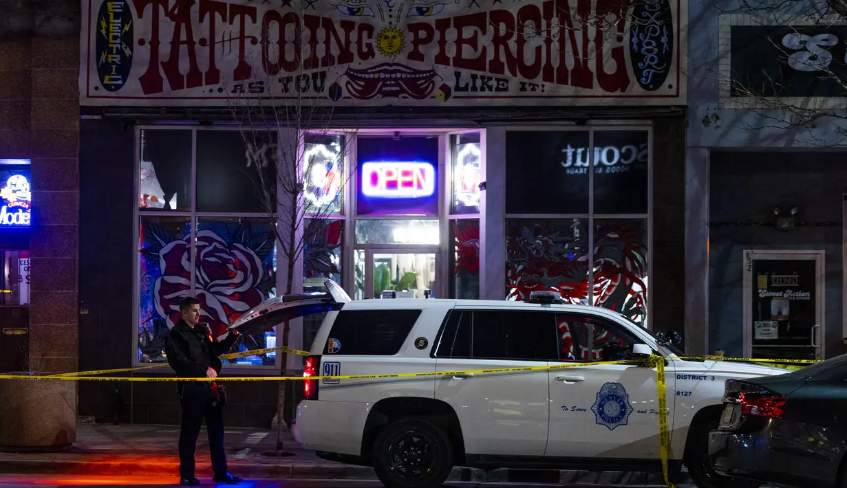 Petugas polisi berdiri di luar toko tato Sol Tribe di Broadway di mana dua wanita tewas dan seorang pria terluka dalam penembakan di Denver, Colorado (27/12/2021). (Michael Ciaglo/Getty Images/AFP)