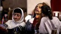 Seorang zombie duduk di meja dengan pengunjung di restoran "Shadows" bertema horor di kota hiburan Boulevard, Riyadh, Arab Saudi, 19 Januari 2022. Restoran tersebut menawarkan pengalaman unik kepada pelanggan dari hidangan dengan tengkorak dan darah ditemani zombie serta vampir (Fayez Nureldine/AFP)