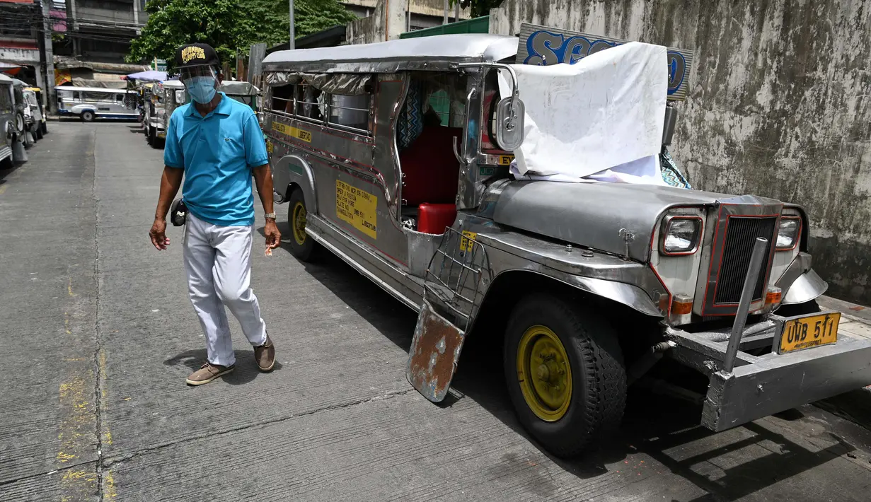 Warga melewati jeepney yang berfungsi sebagai rumah sementara yang diparkir di sepanjang jalan di Manila, 12 Agustus 2020. Angkutan ikonik di Filipina itu belum dapat mengangkut penumpang sejak Maret akibat lockdown Covid-19 yang membuat jutaan orang kehilangan pekerjaan. (Ted ALJIBE/AFP)