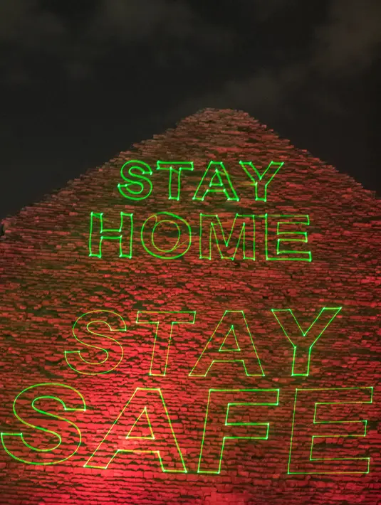 Piramida Besar Kheops memproyeksikan tulisan  "Stay home, stay safe" di tengah penyebaran pandemi corona Covid-19 di Giza, Mesir, Senin (30/3/2020). Piramida tersebut menampilkan pesan persatuan dan solidaritas bagi mereka yang memerangi virus corona di seluruh dunia. (Khaled DESOUKI/AFP)
