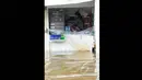 Pedagang menunggu surutnya air yang menggenangi warungnya di kawasan Grogol, Jakarta, Rabu (11/2). Hingga kini sejumlah kawasan di Jakarta masih tergenang banjir akibat dari hujan yang mengguyur  sejak Minggu (8/2). (Liputan6.com/Faisal R Syam)