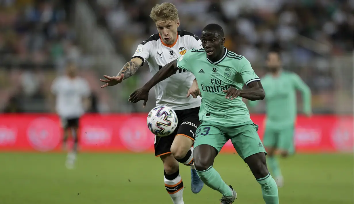 Pemain Valencia, Daniel Wass berusaha merebut bola yang dibawa bek Real Madrid, Ferland Mendy pada pertandingan semifinal Piala Super Spanyol di stadion King Abdullah di Jiddah, Arab Saudi, Rabu, (8/1/2020). Madrid menang 3-1 atas Valencia. (AP Photo/Hassan Ammar)