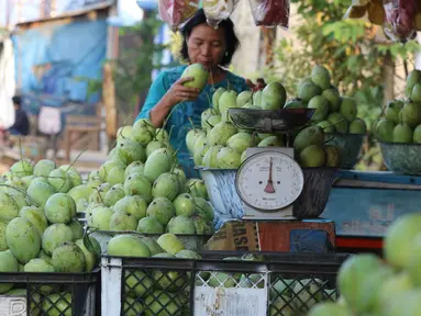 Pedagang menata buah mangga dagangannya yang dijajakan di Jalur Pantura Indramayu, Jawa Barat, Kamis (29/6). Berbagai jenis mangga seperti gedong, arum manis dan golek menjadikan buah ini oleh-oleh khas daerah Indramayu. (Liputan6.com/Helmi Afandi)