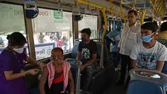 Seorang petugas kesehatan menyuntik pekerja dengan vaksin Covid-19 Covishield di dalam bus penumpang yang diubah menjadi pusat vaksinasi keliling di Kolkata, Kamis (3/6/2021). India telah menderita pandemi yang menghancurkan sejak April, dan baru-baru ini mulai mereda. (Dibyangshu SARKAR/AFP)