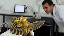 Petugas Museum saat melihat topeng emas Raja Tutankhamun di museum Mesir, Kairo, Selasa (20/10/2015). Para Kolektor dan ilmuwan benda bersejarah sedang melakukan restorasi terhadap topeng emas Raja Tutankhamun. (REUTERS/Mohamed Abd El Ghany)