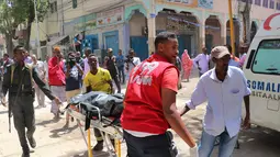 Petugas dibantu warga membawa jenazah korban di lokasi serangan bom mobil di Distrik Hamarwayne, Mogadishu, Somalia (4/2). Menurut Polisi setempat, serangan bom mobil tersebut meledak di dekat sebuah mal di pasar. (AFP Photo/Abdirazak Hussein Farah)