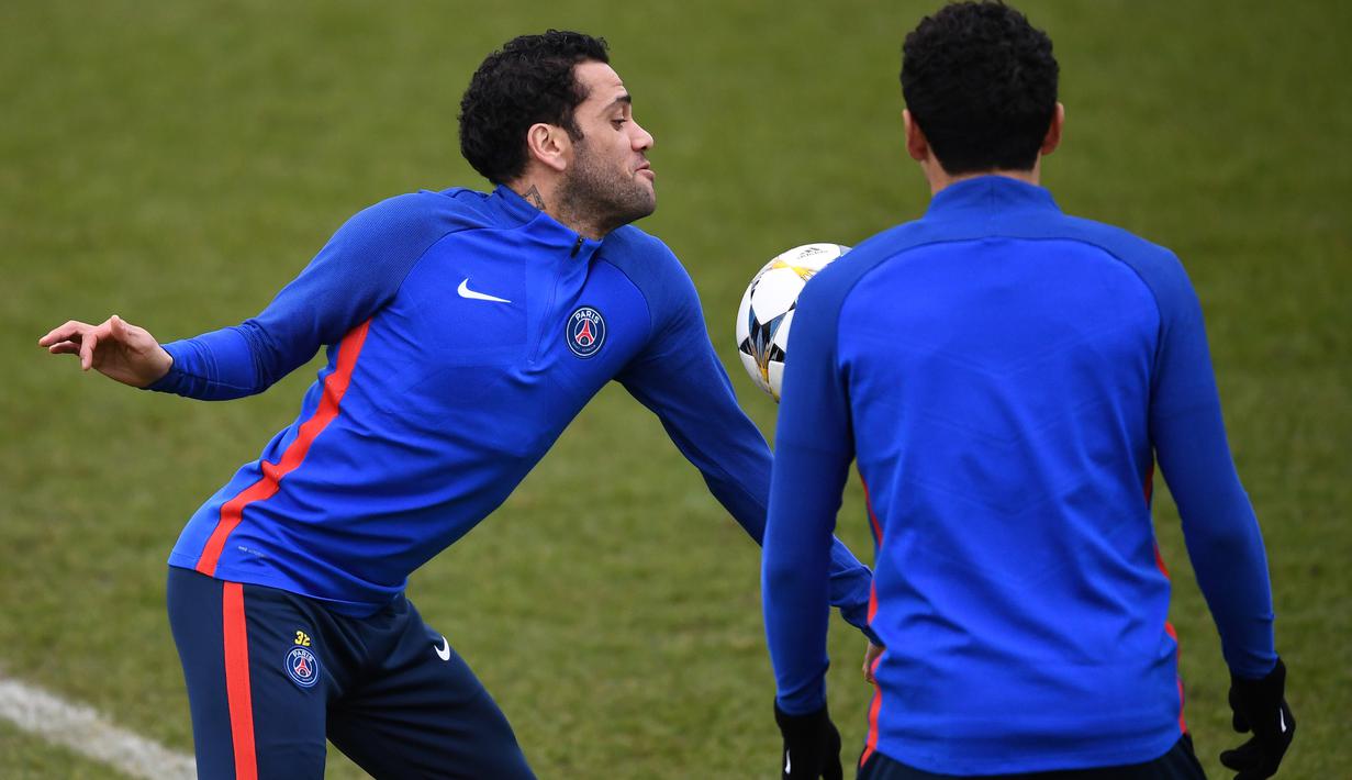 Gaya pemain PSG, Daniel Alves (kiri) menahan bola saat sesi latihan sebelum leg kedua Liga Champions melawan Real Madrid di Ooredoo training center, Saint-Germain-en-Laye,Paris, (5/3/2018). Leg pertama PSG kalah 1-3. (AFP/Franck Fife)