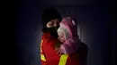 Seorang pekerja dari Inspektorat Situasi Darurat menenangkan bayi yang menangis dari sebuah keluarga yang melarikan diri dari konflik dari negara tetangga Ukraina di perbatasan Rumania-Ukraina, di Siret, Rumania, Sabtu, 26 Februari 2022. (AP Photo/Andreea Alexandru)