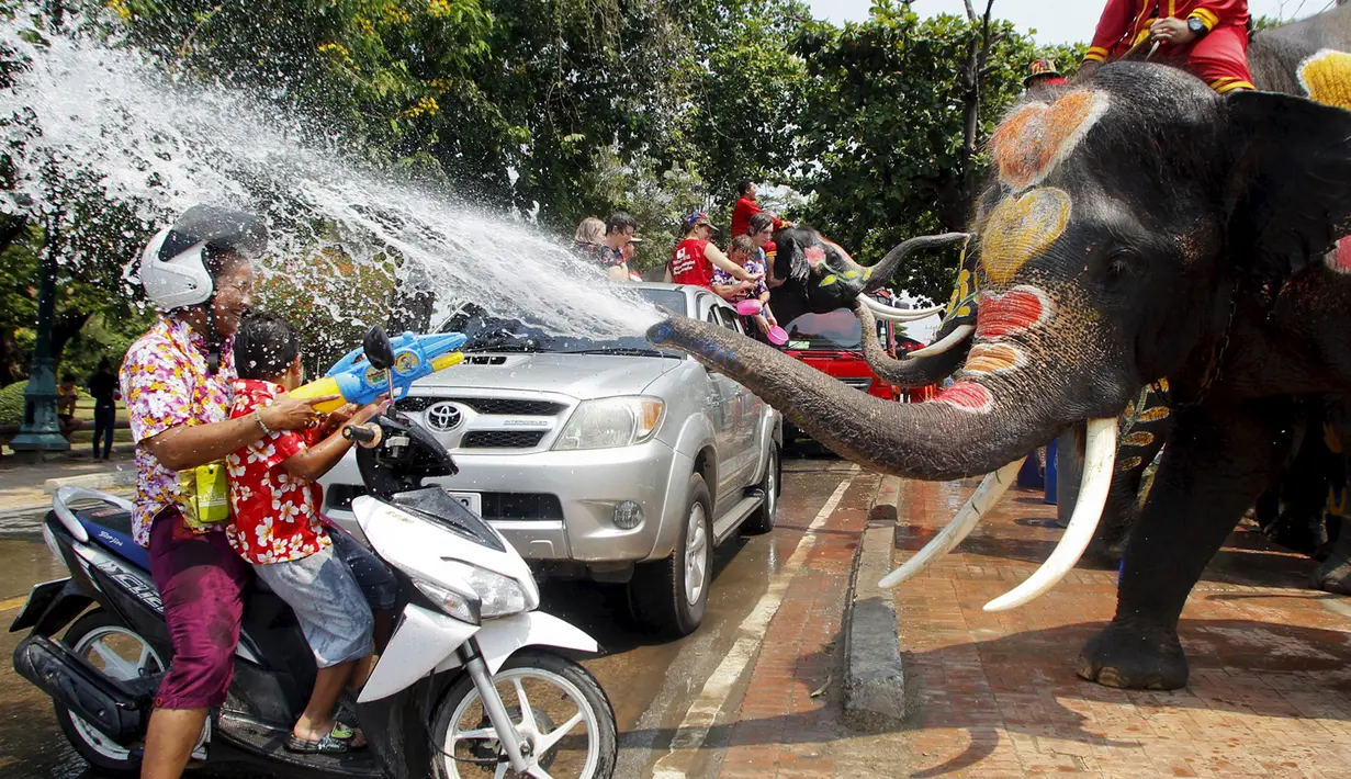 Seorang pengendara sepeda motor menyemprotkan air ke arah gajah saat perayaan festival air Songkran di Ayutthaya, Bangkok, Thailand, Jumat (10/4/2015). Festival air songkoran menandai dimulainya Tahun Baru tradisional Thailand. (REUTERS/Chaiwat Subprasom)