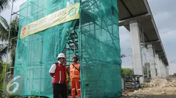 Petugas saat menjaga lokasi proyek pembangunan LRT di Km 13 tol Jagorawi, Jakarta, Minggu (8/1). Proyek tahap pertama LRT cawang-cibubur (14,5 Km) yang kini sudah sampai progress lintas LRT yang nantinya akan terintegrasi MRT. (Liputan6.com/Helmi Affandi)