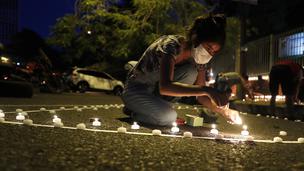 Belen Nunez menyalakan lilin untuk mengenang mereka yang meninggal akibat virus corona di depan Kementerian Kesehatan di Asuncion, Paraguay, Minggu (14/3/2021). Sejuah ini, Paraguay mencatat 3.450 kasus kematian akibat COVID-19. (AP Photo/Jorge Saenz)