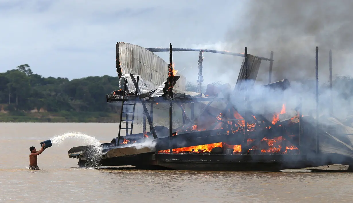 Penambang emas ilegal memadamkan api yang membakar tongkang di Sungai Madeira, Borba, Amazonas, Brasil, 28 November 2021. Institut Lingkungan dan Sumber Daya Alam Terbarukan Brasil membakar lebih dari 60 tongkang untuk menahan penambangan emas ilegal di anak Sungai Amazon. (AP Photo/Edmar Barros)
