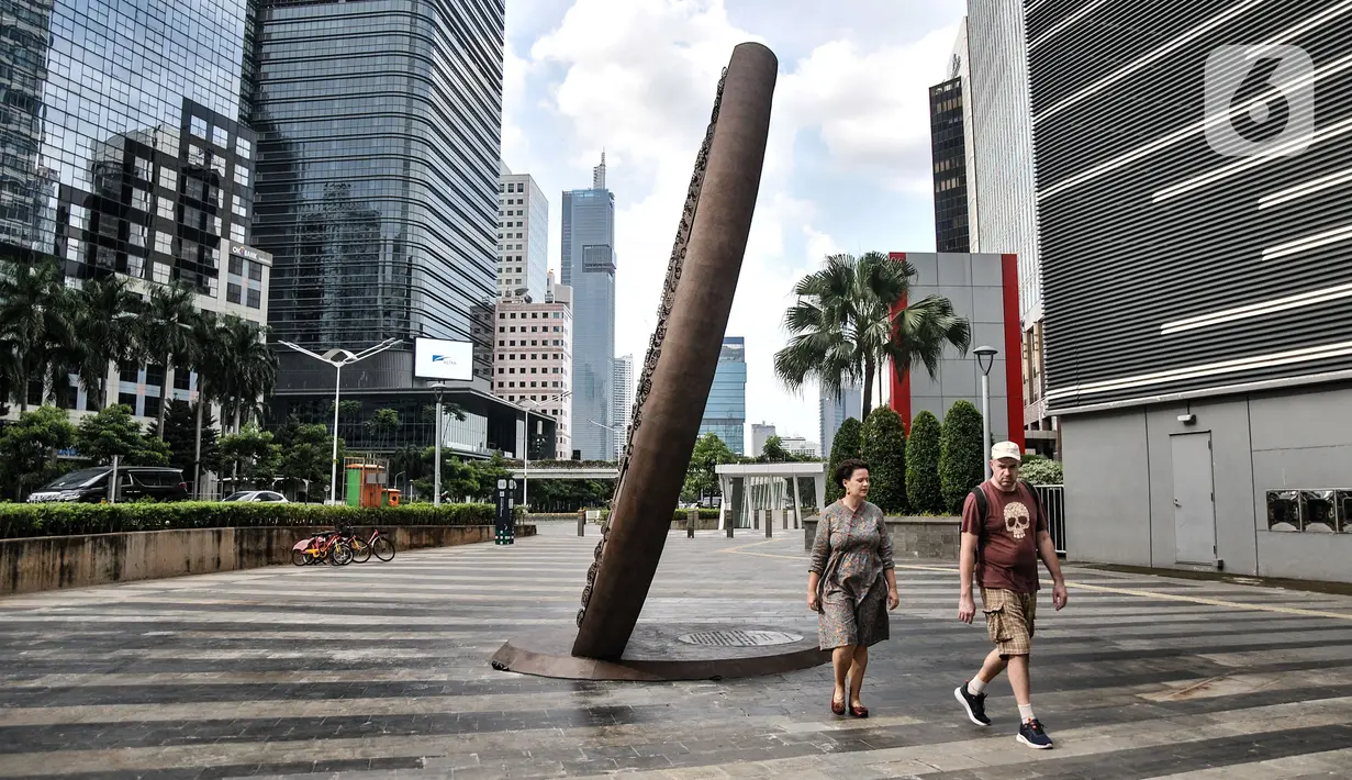 Pejalan kaki melintas dekat Tugu Sepeda di Jalan Jenderal Sudirman, Jakarta Pusat, Minggu (23/10/2022). Tugu tersebut dibangun dengan biaya senilai Rp 800 juta. (merdeka.com/Iqbal S. Nugroho)