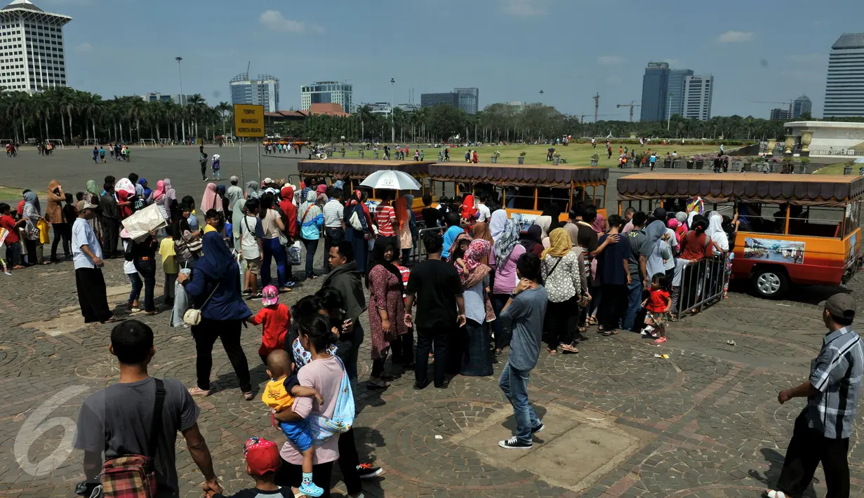 Warga antre untuk menaiki kereta wisata ketika berwisata di Monumen Nasional atau Monas, Jakarta, Minggu (19/7/2015). Ikon kota Jakarta tersebut menjadi tempat wisata alternatif warga saat liburan lebaran. (Liputan6.com/Johan Tallo)