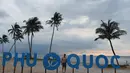 Seorang pengunjung pantai terlihat melewati papan nama di pasir di pulau Phu Quoc selatan Vietnam (19/11/2021). Akhir Desember dan akhir Maret, pulau ini bertujuan untuk menerima hingga 5.000 kedatangan asing dengan penerbangan charter serupa. (AFP/Nhac Nguyen)