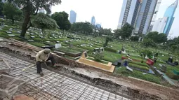 Pekerja menyelesaikan pembuatan saluran air di TPU Karet Bivak, Jakarta, Selasa (22/11). Saluran air tersebut berfungsi mencegah banjir yang sering menggenangi pemakaman setiap diguyur hujan. (Liputan6.com/Immanuel Antonius)
