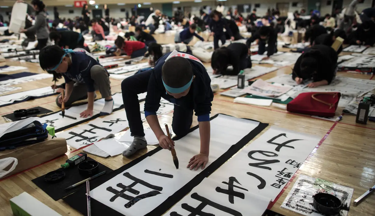 Sejumlah peserta menulis tulisan Jepang saat mengikuti lomba kaligrafi Tokyo, Jepang (5/1). Secara tradisi, masyarakat Jepang biasanya menulis harapan-harapan mereka, atau huruf keberuntungan dalam menyambut tahun baru. (AFP Photo/Behrouz Mehri)