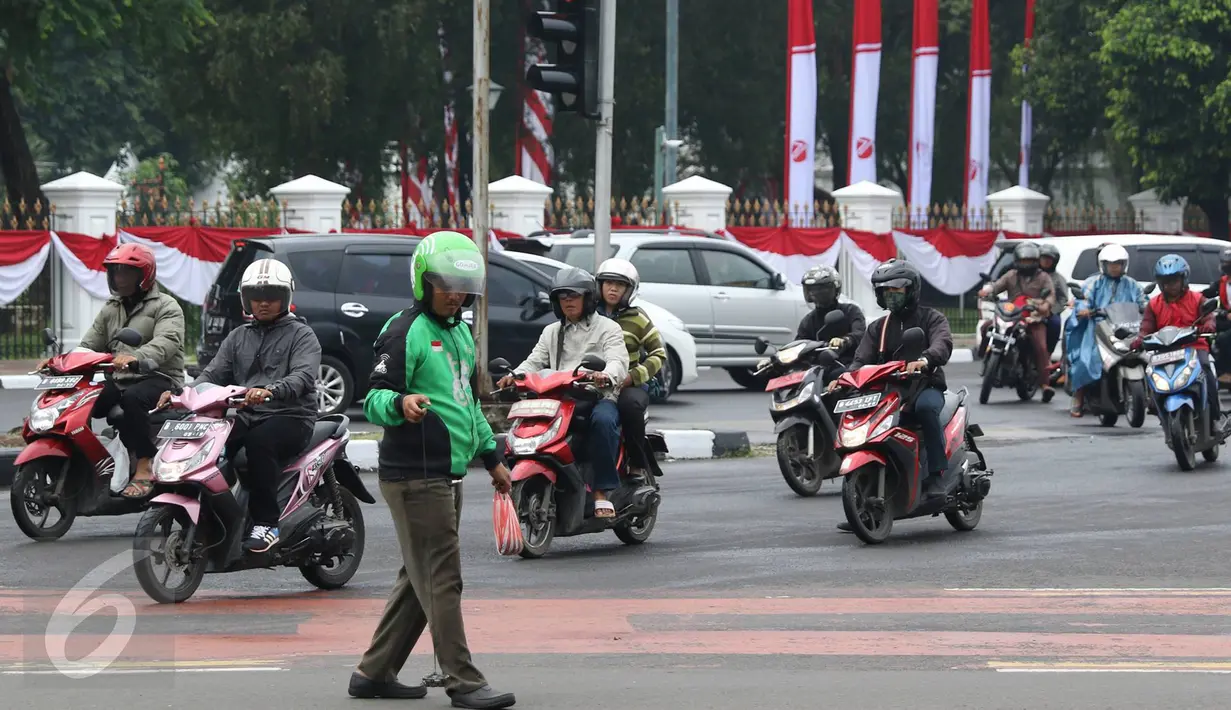Pengendara Gojek bernama Ari mencari ranjau paku yang berserakan di sekitar Istana Negara, Jakarta, Minggu (14/8). Meskipun tak dibayar, Ari berinisiatif untuk mengumpulkan ranjau paku yang merugikan pengendara tersebut. (Liputan6.com/Immanuel Antonius)