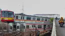 Penumpukan sementara di Depo Depok dilakukan sebagai bagian dari tahapan perucutan sarana KRL sebelum seluruh gerbong dipindahkan ke lokasi konservasi di Stasiun Pasirbungur, Subang, Jawa Barat. Tampak dalam foto, warga melintas di jalan layang dekat Depo Kereta Rel Listrik (KRL) di Jalan Kampung Rawageni, Cipayung, Kota Depok, Jawa Barat, Selasa (20/01/2026). (Merdeka.com/Arie Basuki)