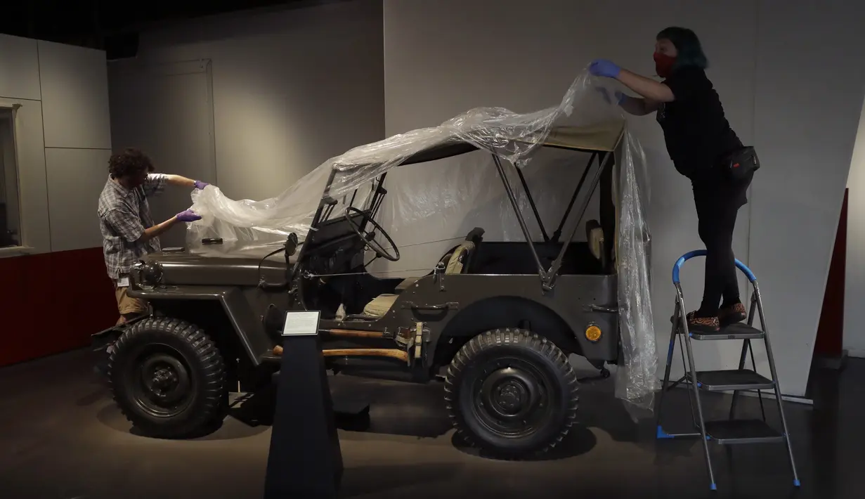 Teknisi membuka penutup Jeep Willys MB Amerika dari Perang Dunia II yang diberikan kepada Palang Merah Inggris di Imperial War Museum, London, Inggris, Rabu (29/7/2020). Museum ini akan kembali dibuka pada 1 Agustus 2020 setelah pemerintah Inggris terus melonggarkan lockdown. (AP Photo/Matt Dunham)