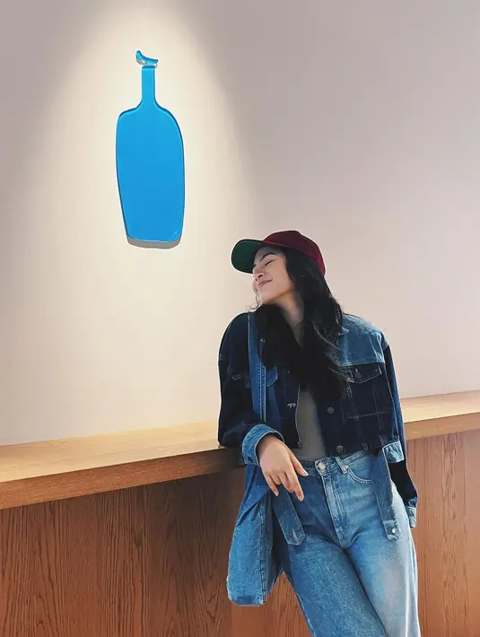 Mengenakan innerwear berwarna abu-abu, Maudy Ayunda melapisinya dengan cropped jacket denim, dipadu dengan celana denim, dan membawa totebag yang juga denim. Maudy menambahkan sentuhan cap berwarna merah dengan inisial huruf H. Foto: Instagram.