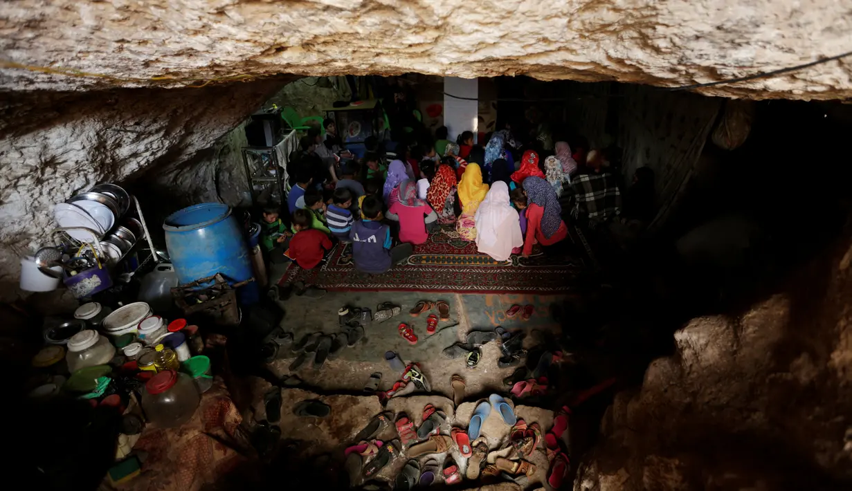 Anak-anak pengungsi  bersiap mengikuti kegiatan belajar di dalam sebuah gua di desa yang dikuasai pemberontak di Tramla, Provinsi Idlib, Suriah, 27 Maret 2016. Gua ini mampu menampung sekitar 120 siswa yang ingin belajar. (REUTERS/Khalil Ashawi)