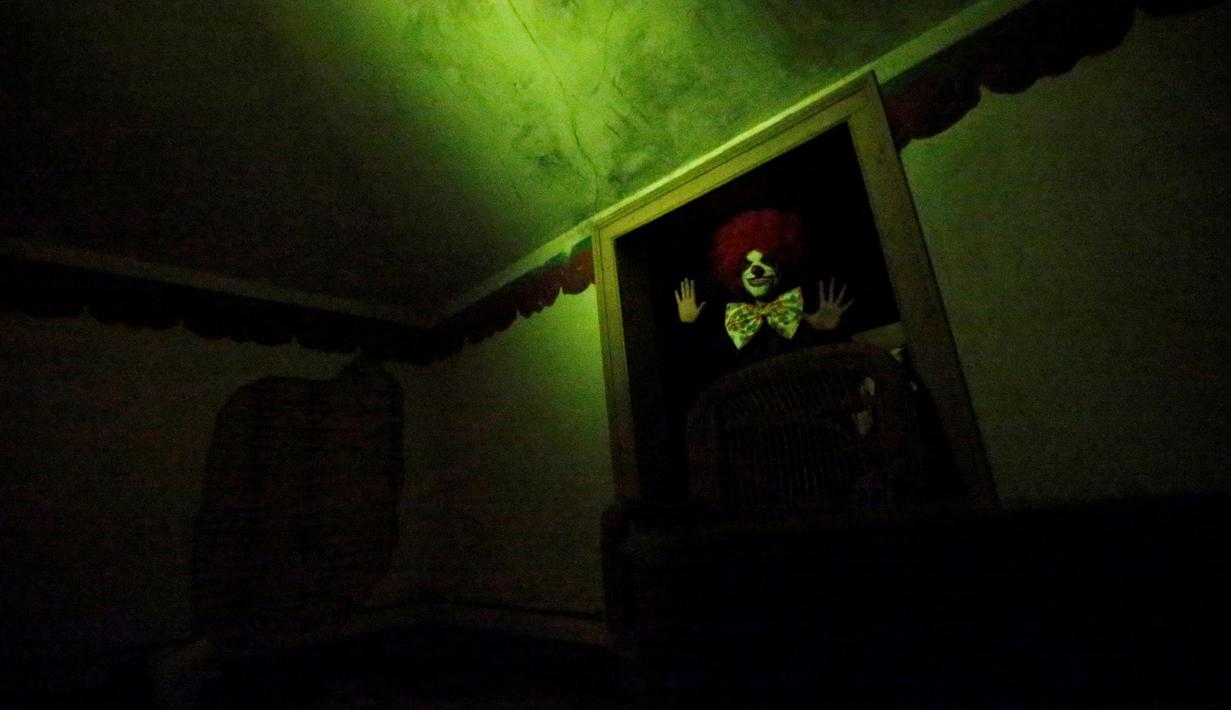 Aktor berkostum badut bersiap menakut-nakuti pengunjung di dalam rumah hantu Quinta Nova da Assuncao di Belas, Portugal (13/5). Pengunjung akan diajak tur di dalam rumah kosong Quinta Nova da Assuncao. (REUTERS/Rafael Marchante)