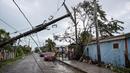 Orang-orang berdiri di jalan dengan tiang listrik tumbang setelah Badai Lisa di Belize City, Belize, 3 November 2022. Badai Tropis Lisa menyebabkan banjir dan membuat sebagian negara itu menjadi gelap gulita. (Johan ORDONEZ/AFP)