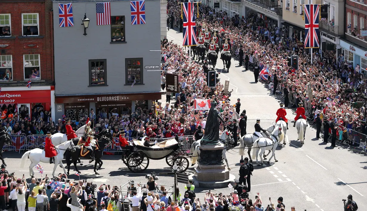 Pangeran Harry dan Meghan Markle menaiki kereta kencana usai prosesi pernikahan mereka di Kastil Windsor, Inggris, Sabtu (195). Warga Inggris bersuka cita menyambut pernikahan Pangeran Harry dengan Meghan Markle. (Andrew Matthews/pool photo via AP)