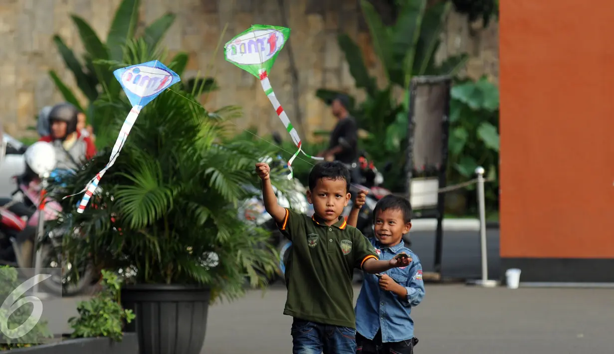 Dua orang anak berusaha menerbangkan layang layang saat bermain di Lapangan Monumen Tugu Pancasila TMII, Jakarta, Jumat (8/7). TMII masih menjadi lokasi favorit warga menghabiskan libur hari raya. (Liputan6.com/Helmi Fithriansyah)