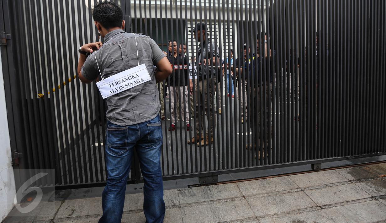 Salah satu adegan saat tersangka, yang perankan pemeran pengganti, mendatangi sebuah rumah lokasi perampokan dan pembunuhan dalam prarekonstruksi di perumahan Pulomas, Jakarta Timur, Jumat (6/1). (Liputan6.com/Faizal Fanani)