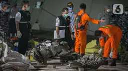 Petugas Basarnas mengumpulkan puing pesawat Sriwijaya Air nomor penerbangan SJ 182 rute Jakarta-Pontianak pada hari ketujuh operasi SAR pesawat tersebut di JICT II Tanjung Priok, Jakarta Utara, Jumat (15/1/2021). (Liputan6.com/Faizal Fanani)