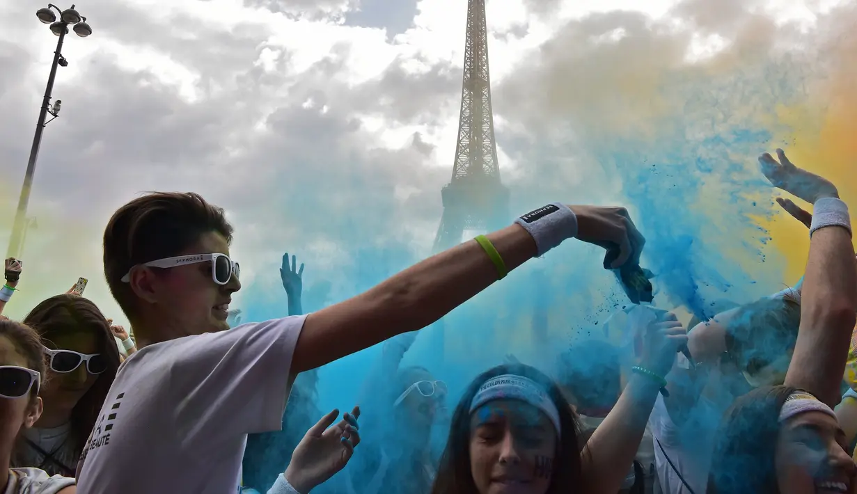 Peserta menaburkan serbuk warna saat acara Color Run 2017 di depan Menara Eiffel, Paris, Minggu (16/4). Panitia mengklaim bahwa serbuk yang mereka gunakan aman untuk manusia. (AFP PHOTO / CHRISTOPHE ARCHAMBAULT)