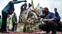 Massa buruh menaburkan bunga sebagai simbol duka atas kebijakan pemerintah di kawasan Patung Kuda, Jakarta, Senin (2/11/2020). Buruh dari berbagai serikat pekerja menggelar demo terkait penolakan pengesahan omnibus law Undang-Undang Cipta Kerja dan upah minimum 2021. (merdeka.com/Iqbal S Nugroho)