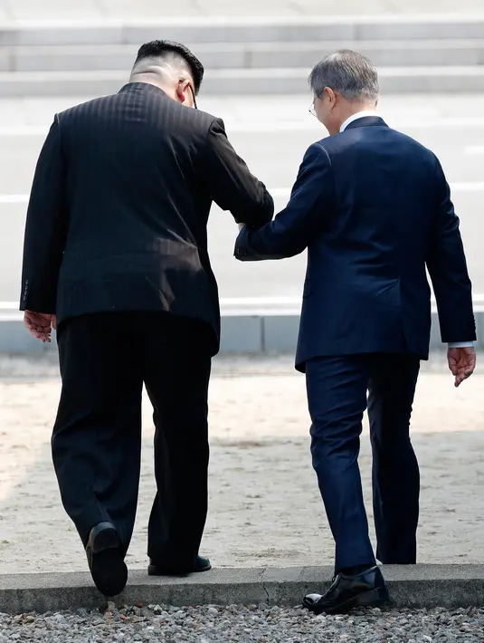 Pemimpin Korea Utara, Kim Jong-un mengajak Presiden Korea Selatan, Moon Jae-in melintasi perbatasan ke wilayah Korea Utara di Zona Demiliterisasi (DMZ), Jumat (27/4).  Untuk pertama kalinya setelah lebih dari satu dekade, pemimpin dua Korea bertemu (AP)