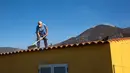 Felix Rodriguez Luis (61) membersihkan abu dari atap rumahnya, yang terletak di zona eksklusi setelah letusan gunung berapi Cumbre Vieja, di lingkungan Las Manchas di Pulau La Palma, Spanyol pada 4 Januari 2022. Selama berminggu-minggu mereka bermimpi untuk kembali ke rumah. (DESIREE MARTIN/AFP)