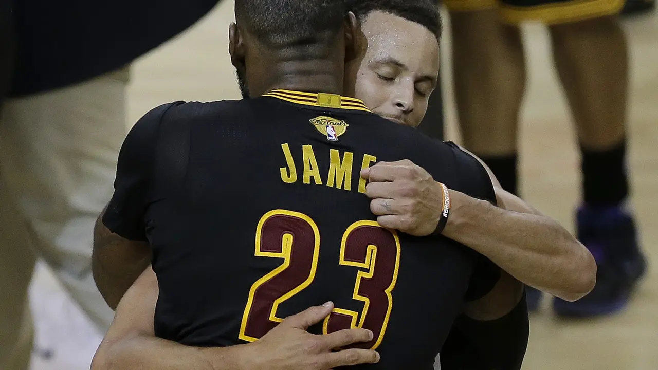 Guard Golden State Warriors, Stephen Curry, memeluk forward Cleveland Cavaliers, LeBron James, usai gim 5 final NBA 2017. Curry membantu Warriors menang 4-1 dan jadi juara. 