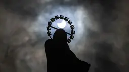 Siluet Patung Our Lady, Star Of The Sea saat gerhana matahari parsial di langit di Bull Wall, Dublin, Kamis (10/6/2021). Fenomena gerhana matahari cincin memperlihatkan bulan tidak sepenuhnya menutup seluruh bagian matahari sehingga bagian pinggir bulan terlihat bercahaya. (Brian Lawless/PA via AP)