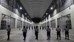 Penjaga sipil dari Direktorat Jenderal Penjara berdiri di luar sel tahanan saat tur media di Pusat Pengurungan Terorisme, Tecoluca, El Salvador, 2 Februari 2023. Menurut pemerintah, penjara besar yang masih dalam pembangunan tersebut memiliki kapasitas maksimum 40.000 narapidana dan dimaksudkan untuk memenjarakan anggota geng. (AP Photo/Salvador Melendez)