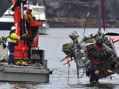Kepolisian New South Wales dan petugas penyelamat mengangkat bangkai pesawat amfibi yang jatuh di Sungai Hawkesbury, utara Sydney, Kamis (4/1). Bangkai kapal diangkat dari dasar sungai ke sebuah tongkang. (Mick Tsikas/AAP Images via AP)
