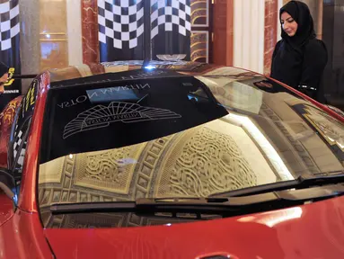 Dua wanita Saudi melihat sebuah mobil di sebuah pameran mobil di resor Jeddah Laut Merah Jeddah (5/10). Pada bulan September 2017 Kerajaan Arab Saudi mengeluarkan dekrit yang memperbolehkan wanita untuk mengendarai mobil. (AFP Photo/Amer Hilabi)