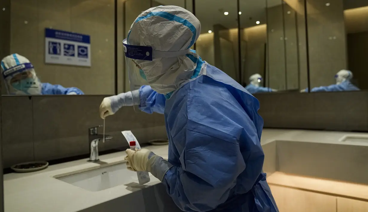 Seorang pekerja medis mengumpulkan sampel di toilet pria untuk pengujian COVID-19 di pusat media utama di Olimpiade Musim Dingin 2022 di Beijing, 11 Februari 2022. Tak hanya manusia, penyelenggara Olimpiade juga melakukan tes pada gagang pintu, tombol lift, sofa dan mesin ATM. (AP Photo/Jae C.Hong)