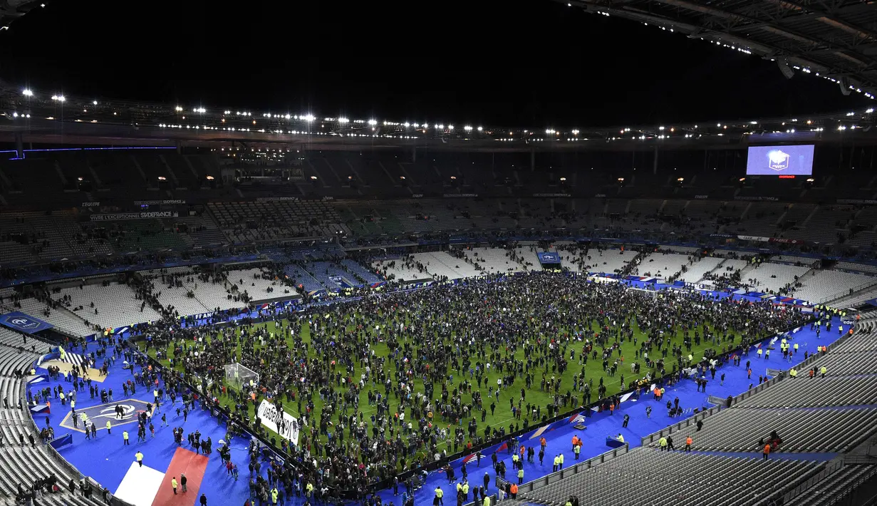 Ribuan Penonton berhamburan di lapangan stadion Stade de France saat menyaksikan pertandingan persahabatan antara Prancis melawan Jerman di Saint-Denis, Paris, (13/11). Serangan bom terjadi di dekat stadion Stade de France Prancis. (AFP PHOTO/FRANCK FIFE)