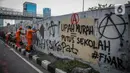 Petugas PPSU membersihkan coretan yang mengotori pembatas jalan pascaunjuk rasa di kawasan DPR/MPR, Jakarta, Jumat (17/7/2020). Coretan tersebut dilakukan oleh massa yang menolak RUU Omnibus Law Cipta Lapangan Kerja di depan Gedung DPR pada Kamis (16/7) kemarin. (Liputan6.com/Faizal Fanani)