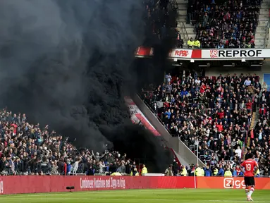 Asap hitam menyelimuti tribun penonton saat pertandingan sepak bola PSV Eindhoven vs Ajax dalam pertandingan Liga Eredivisie di Stadion Philips, Belanda (23/4). Asap hitam tebal tersebut sempat mengganggu jalannya pertandingan. (Olaf KRAAK / ANP / AFP)