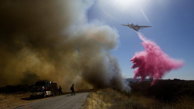 Sebuah kapal tanker menjatuhkan air saat memadamkan api di Cherry Valley, California (1/8/2020). Sebanyak 7.800 warga dievakuasi  akibat kebakaran hutan yang menghanguskan sekitar 4.000 hektar lahan pada akhir pekan kemarin. (AP Photo/Ringo H.W. Chiu)