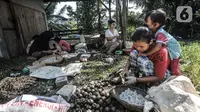 Pekerja perempuan membawa anak saat bekerja mengupas buah aren di Kampung Citugu, Desa Puraseda, Leuwiliang, Kabupaten Bogor, Jawa Barat, Minggu (25/4/2021). Dalam sehari, satu petani di kampung ini mampu menghasilkan 80-100 kg kolang-kaling. (merdeka.com/Iqbal S. Nugroho)