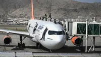 Orang-orang Afghanistan naik ke atas sebuah pesawat saat mereka menunggu di bandara Kabul (16/8/2021). Ribuan orang mencoba melarikan diri dari Taliban yang segera menguasai penuh Afghanistan. (AFP/Wakil Kohsar)