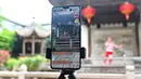 Seorang staf tampil livestreaming melalui ponsel di kawasan sejarah dan budaya di Fuzhou, Provinsi Fujian, China (19/5/2020). Otoritas setempat melakukan livestreaming melalui ponsel untuk memungkinkan masyarakat di mana pun untuk menikmati keindahan budaya lokal. (Xinhua/Lin Shanchuan)